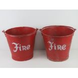 A pair of red painted galvanized steel 'fire' buckets, each with swing handle over, 33.5cm diameter.