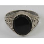 A mens silver and onyx signet ring having engraved decoration to shoulders,