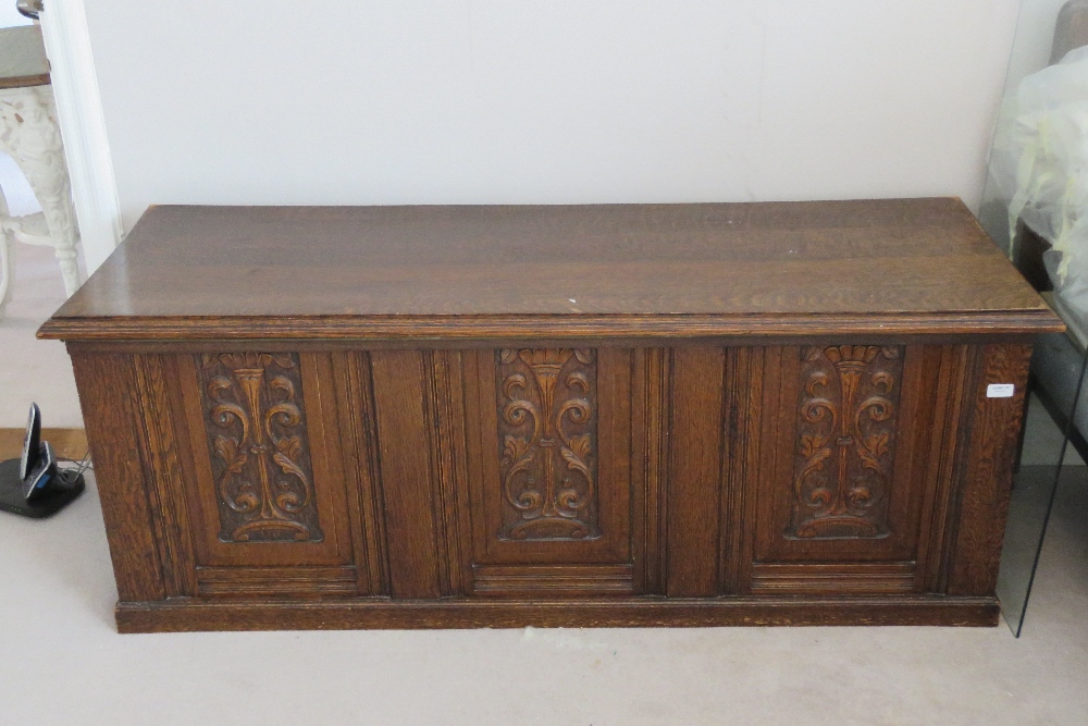 A carved oak panel fronted marriage chest, lid lifting to reveal plain compartment within,