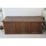 A carved oak panel fronted marriage chest, lid lifting to reveal plain compartment within,
