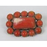 A 19th century red coral mourning brooch having glazed locket to back,