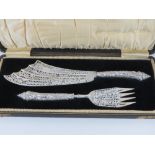 An ornate Victorian set of HM silver fish servers having pierced and repoussé fish themed pattern