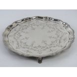 An HM silver salver raised over four scroll work feet having floral engraving upon and hallmarked