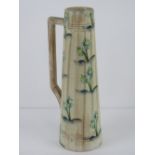 A c1930s Radford tall ewer with handle, hand painted with flowers upon, standing 33cm high. A/f.