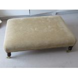 A contemporary large footstool in gold coloured upholstery,