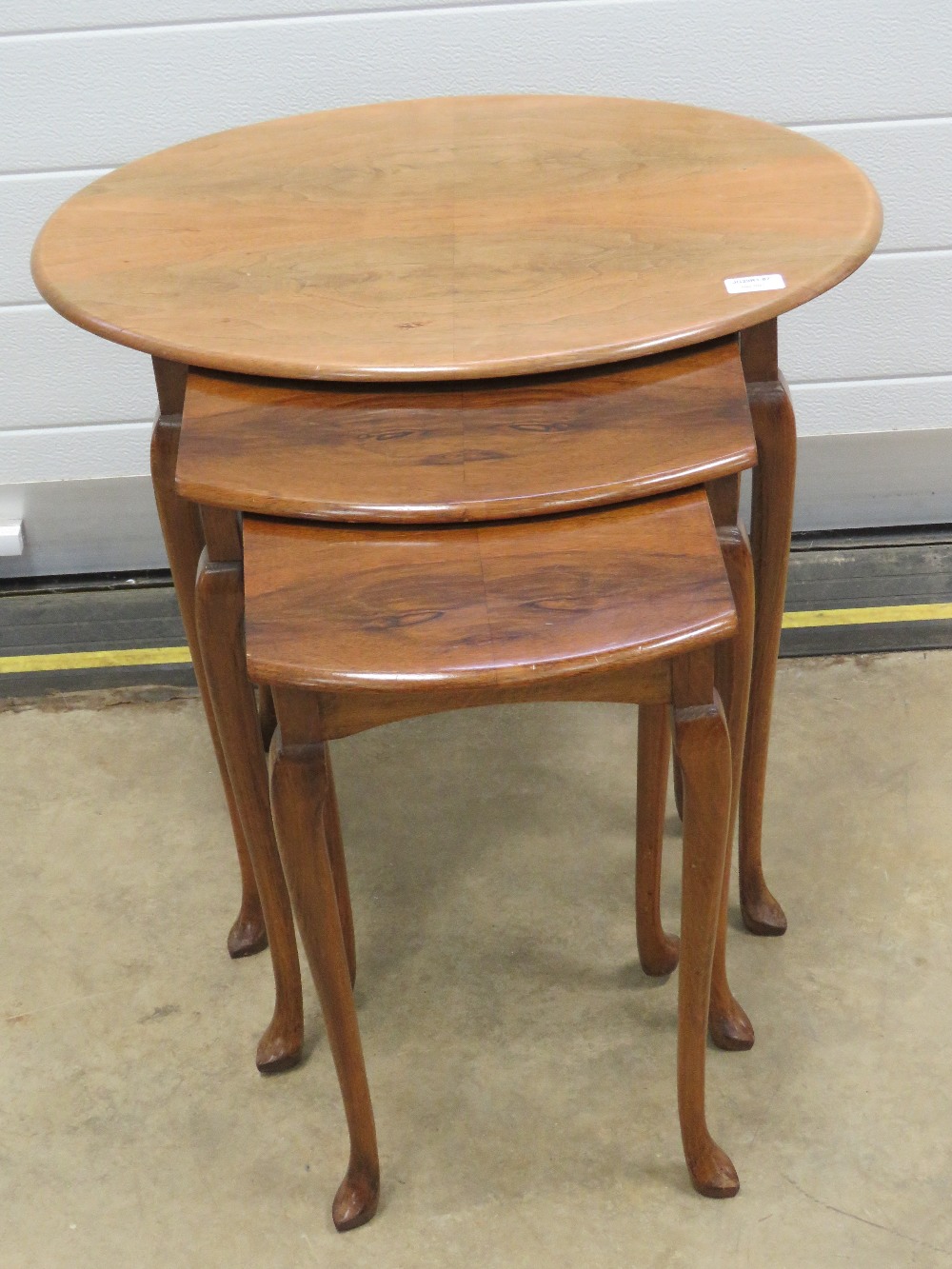 A nest of three 20th century walnut tables raised over slender taping legs, 60,