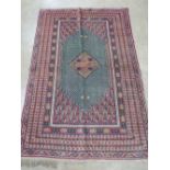 A green and pink ground woollen rug having geometric pattern upon,