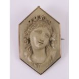 A carved lava stone cameo being a three dimensional female portrait with floral crown,