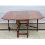 A substantial oak drop leaf table having unusual shaped top over barley twist base with gate legs