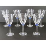 A set of seven hand blown wine glasses having mottled blue bead to stem,