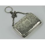 A white metal coin purse on chain having floral engraving throughout and central monogram shield