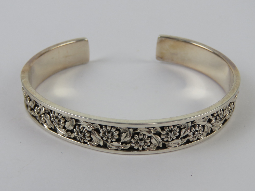 An HM silver bangle having floral decoration set with round cut diamonds, approx 6.5 x 5.