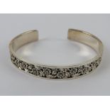 An HM silver bangle having floral decoration set with round cut diamonds, approx 6.5 x 5.