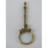 A 925 silver magnifying glass pendant having floral decoration and gilded, measuring 8.3cm inc bale.