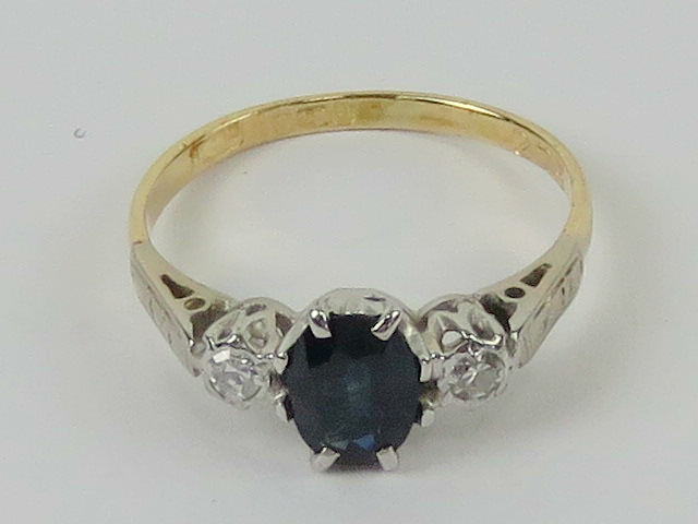 An 18ct gold sapphire and diamond ring, the central blue oval cut sapphire approx 0.