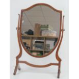 An Edwardian mahogany shield shaped toilet mirror raised over H shaped base, 61cm high, 41cm wide.
