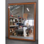 A contemporary wooden framed bevelled edge wall mirror, 112 x 88cm.