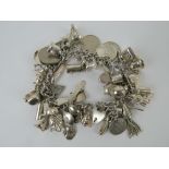 A charm bracelet profusely adorned with silver and white metal charms inc 'opera glasses' stamped