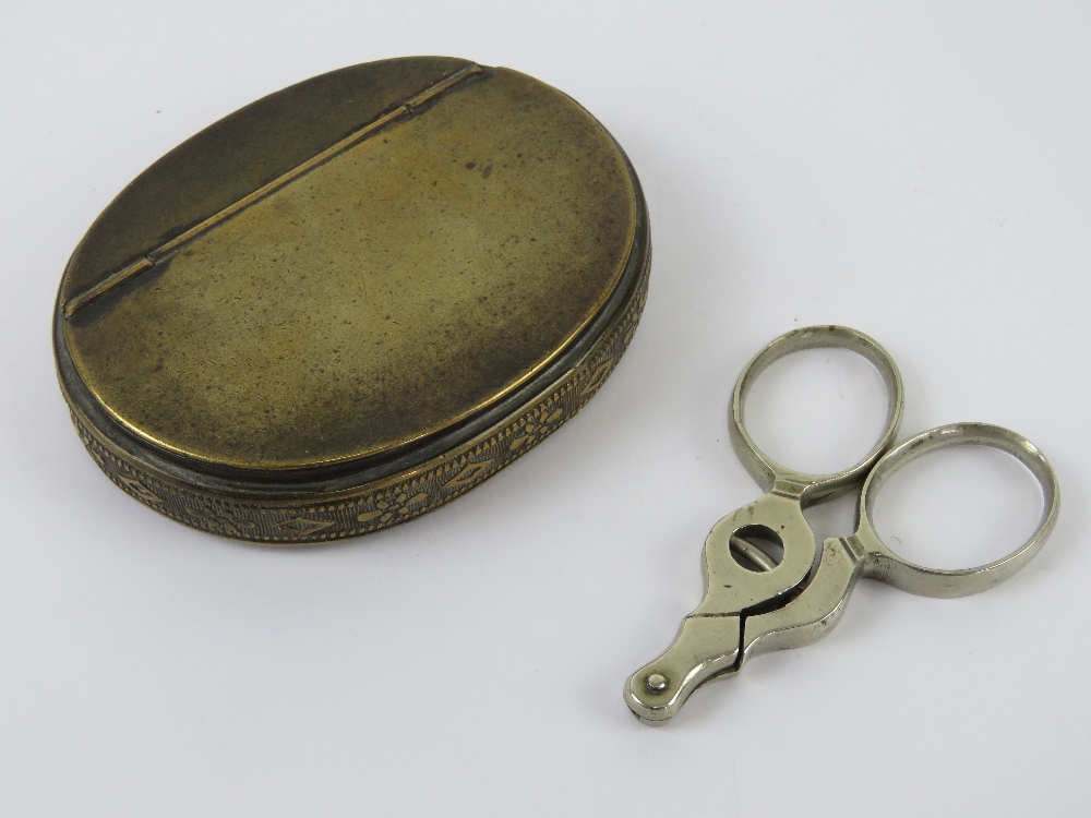 A brass snuff box of oval form with hinged lid, 8cm wide. Together with a cigar cutter. Two items.