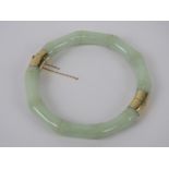 A 14ct gold and jade bangle, the pale opaque green jade carved into a bamboo pattern,