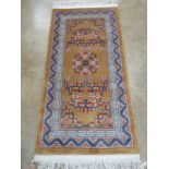 A Chinese woollen rug, gold ground with blue and pink floral design upon,