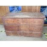 A plank-top pine mule chest, lid lifting to reveal compartment within.