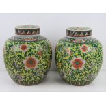 A pair of Oriental lidded ginger jars in yellow ground with green and orange floral decoration upon,