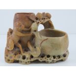 A carved soapstone brush pot featuring a monkey and fruit upon, 16.5cm wide.
