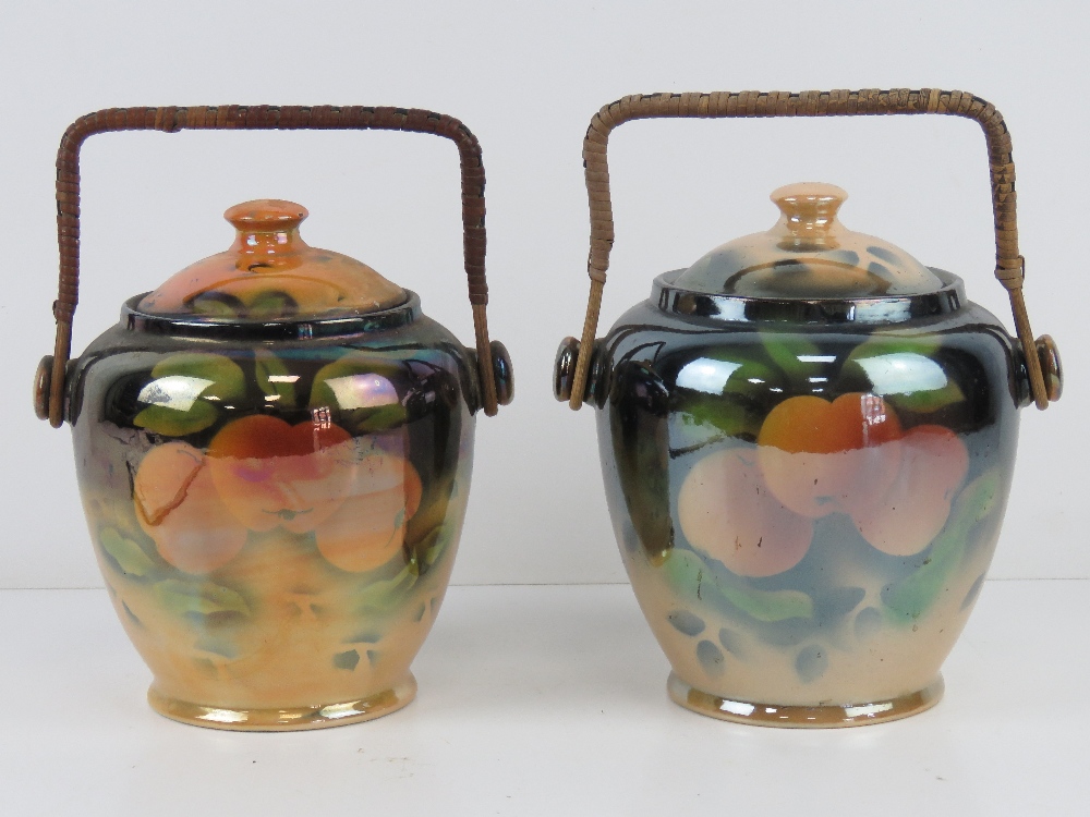 Two ceramic pearlescent wafer / biscuit barrels each with wicker handle and fruit design upon.