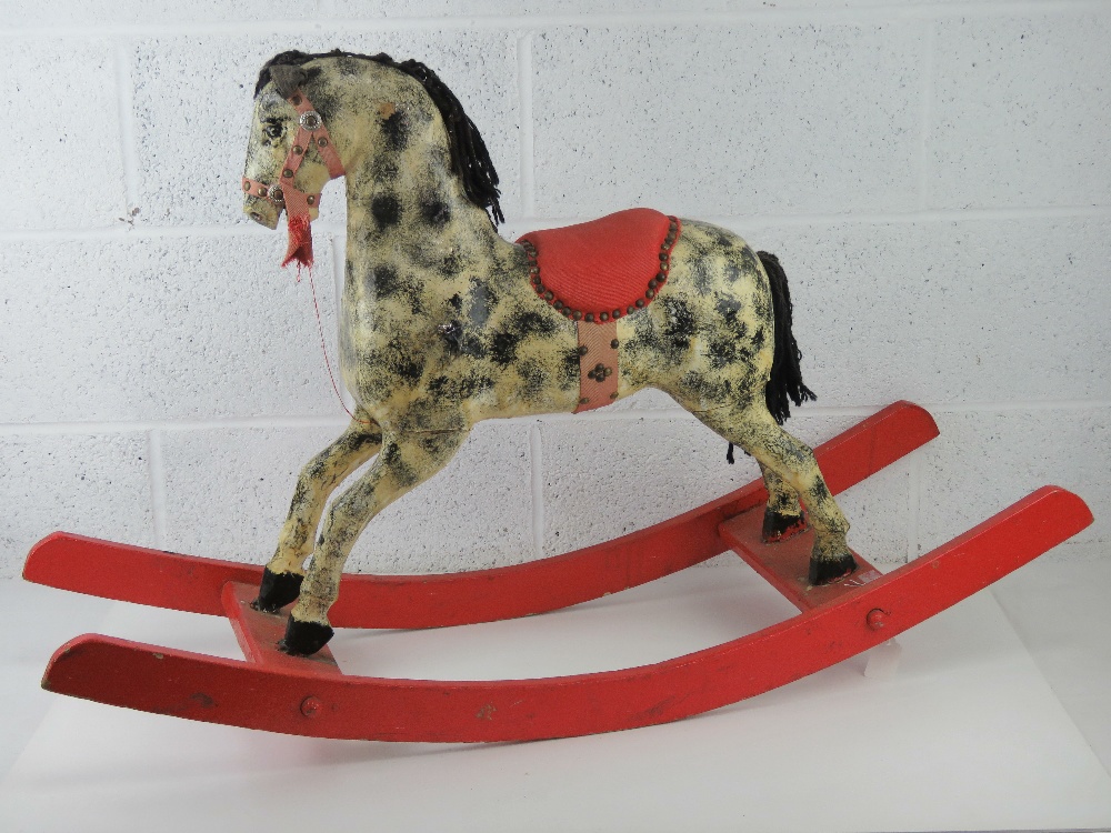 A vintage rocking horse being black and grey dapple on red rockers having fabric saddle,