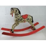 A vintage rocking horse being black and grey dapple on red rockers having fabric saddle,