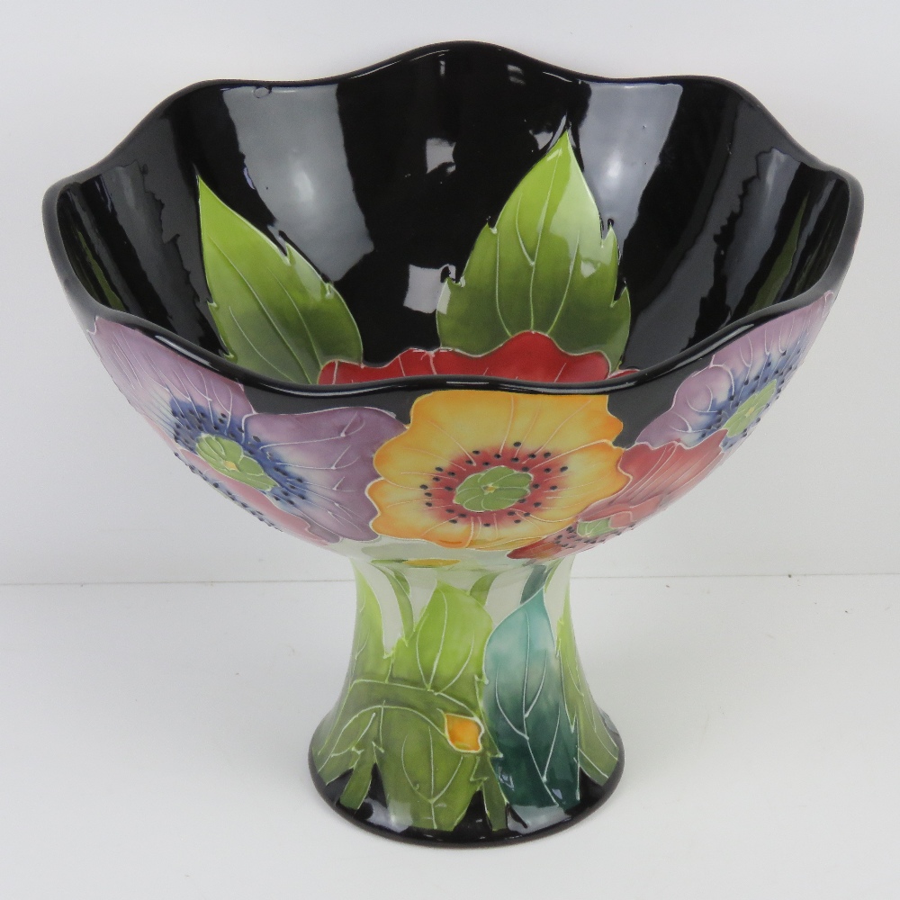 A large ceramic pedestal bowl having flo