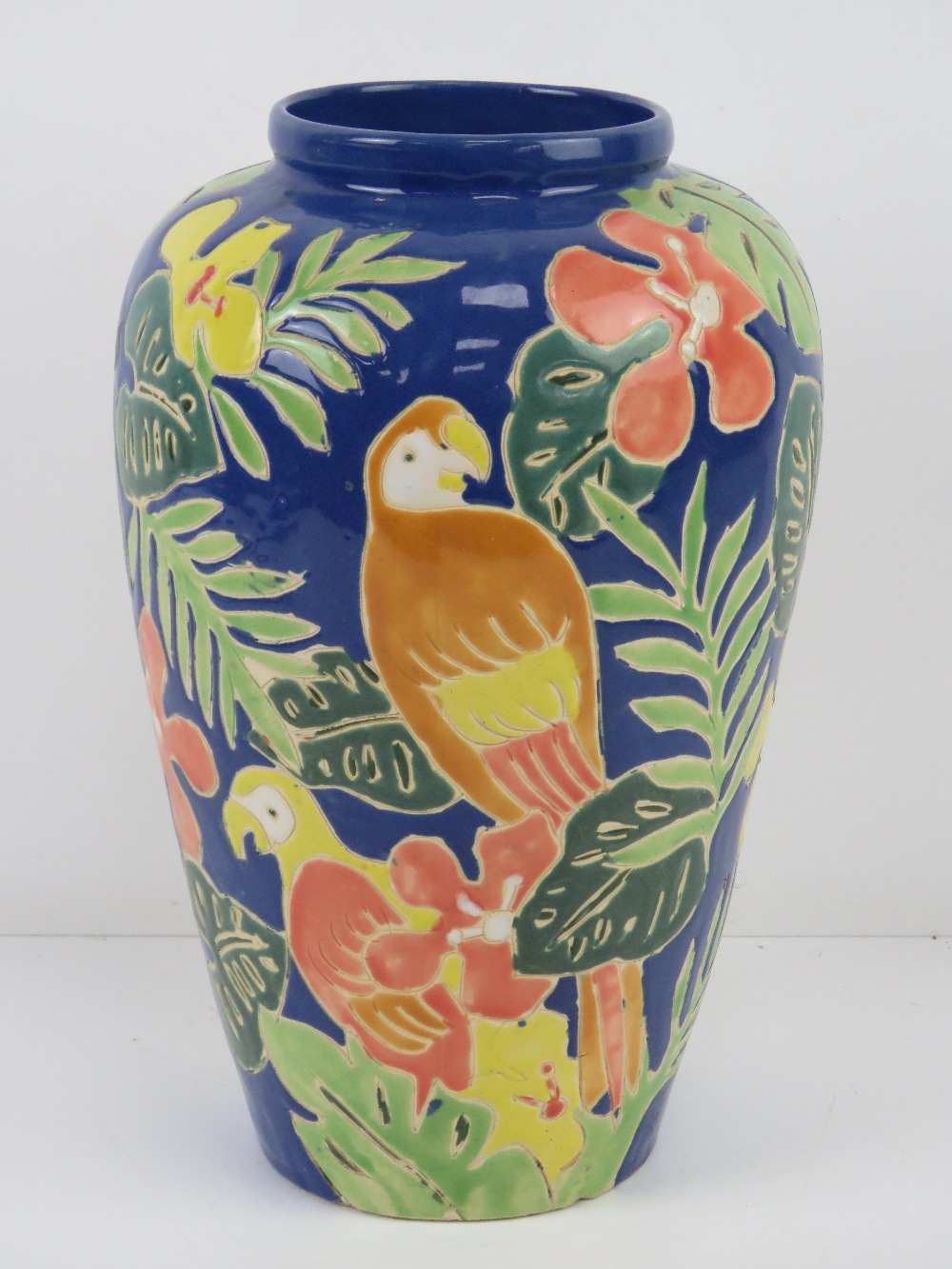 A glazed vase having tropical foliage an