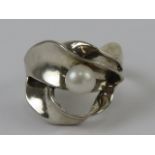 An abstract design silver and pearl ring