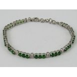 A silver tennis bracelet set with green