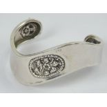 A silver bangle having carved floral dec