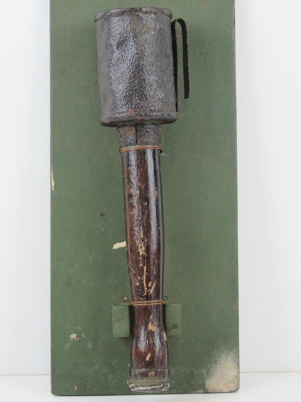An inert WWI German stick grenade, mounted on board for display purposes, board measuring 42 x 18cm.