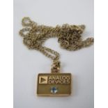 A 14k gold square shaped pendant marked 'Analog Devices' and having white stone under, stamped 14k,