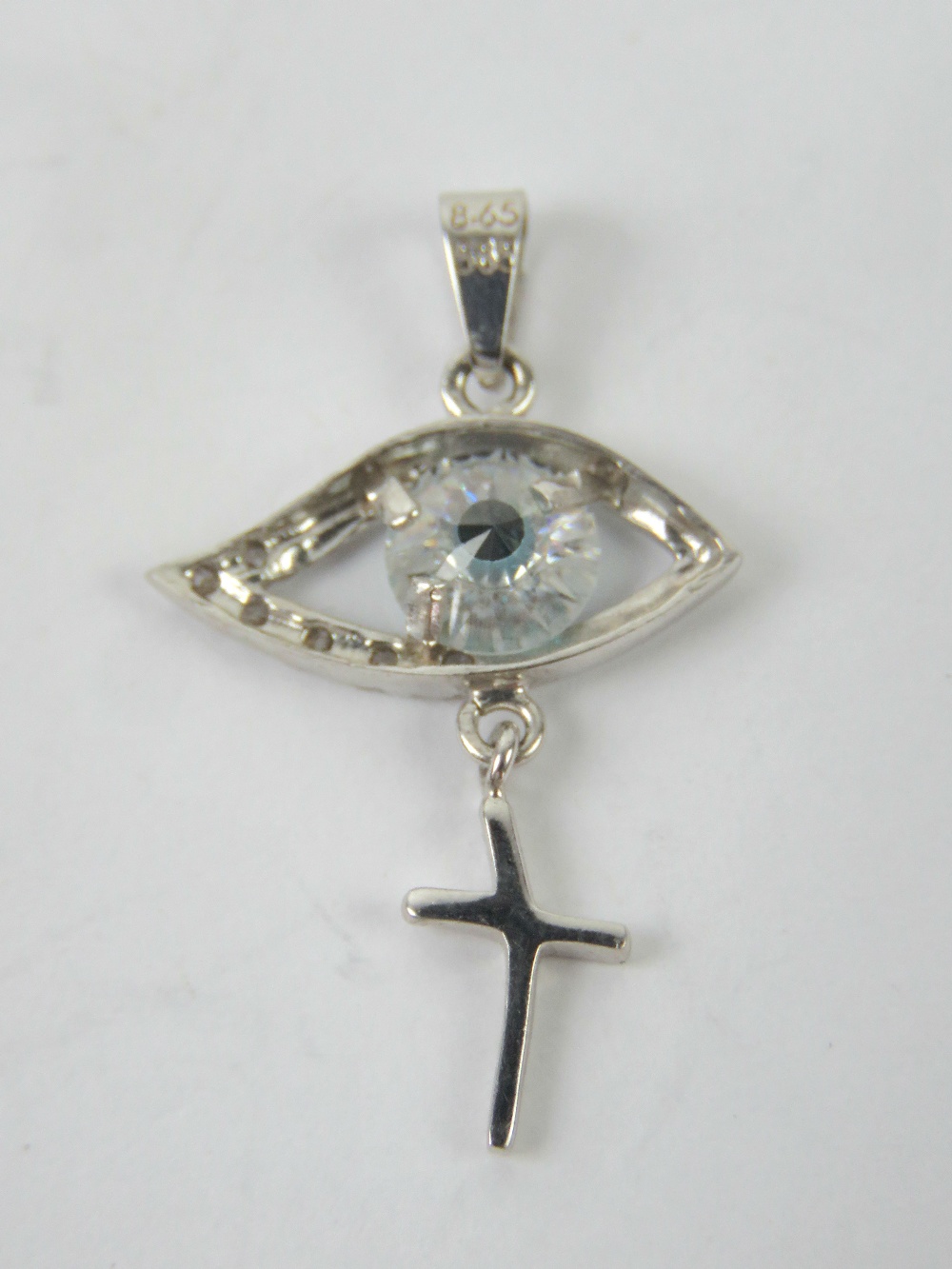 A 14ct white gold pendant in the form of an eye with cross suspended below, stamped 585 14k,