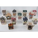 A quantity of assorted ceramic teapots in the form of shops and houses.