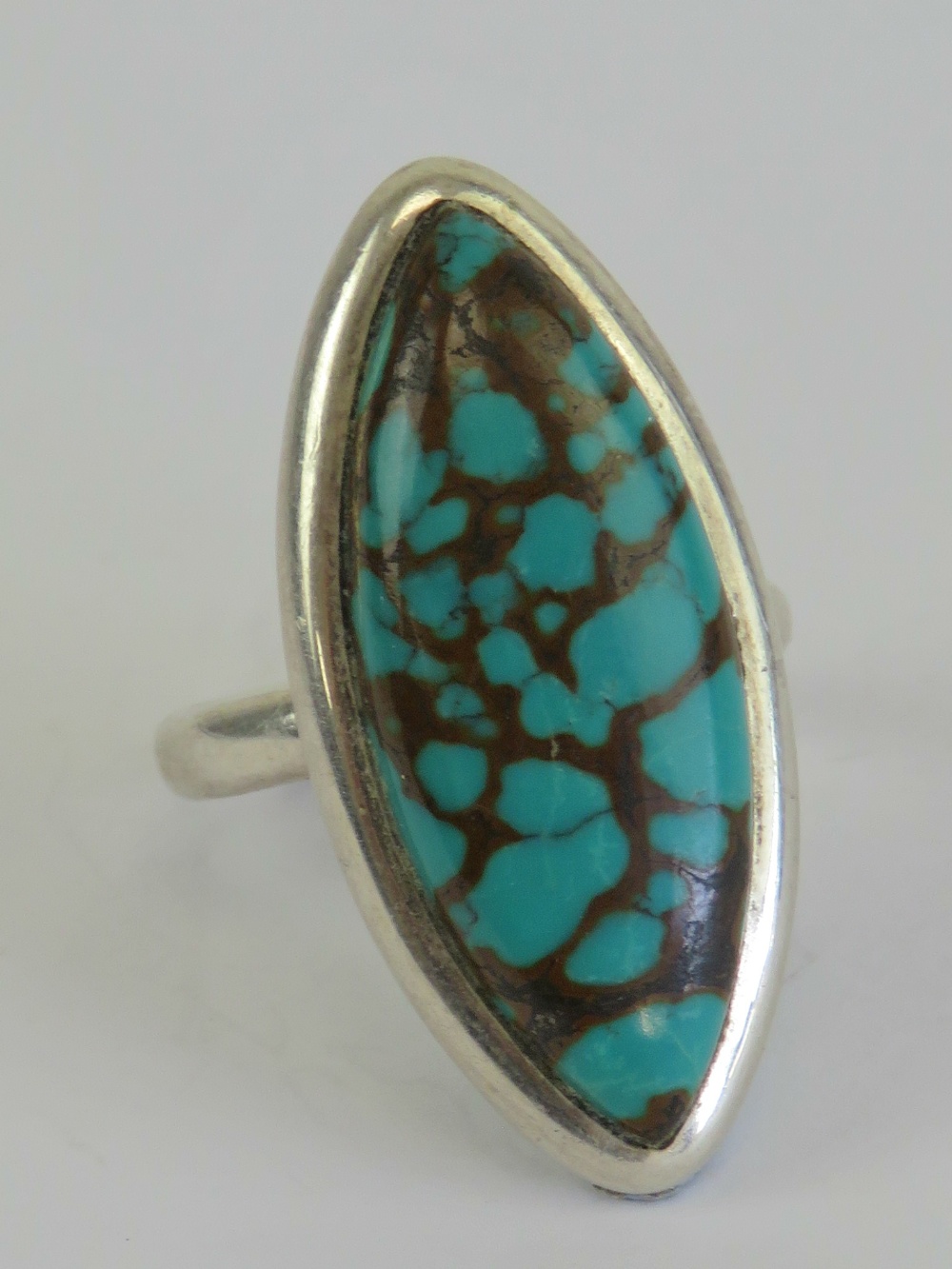 A silver and turquoise cocktail ring, the marquise cabachon of good green hue,