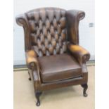 A brown leather wing back armchair,