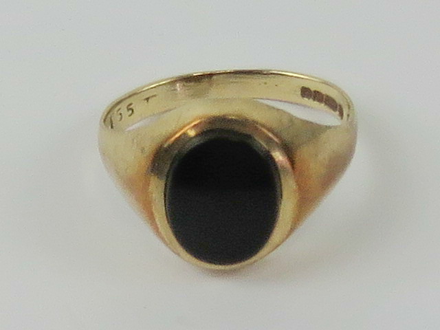 A 9ct gold and onyx signet ring, unengraved oval stone, hallmarked 375, size M, 2.