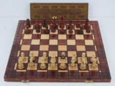 A contemporary travel chess set having carved wooden pieces within.