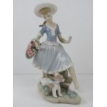 Lladro figurine of a girl with a basket of pink flowers and puppy at feet, standing 26.5cm high.