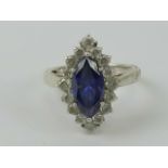 A silver cocktail ring having central marquise cut blue/purple stone surrounded by round cut white