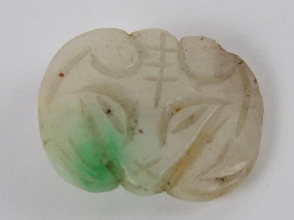 A single jade button 'mutton fat' white with green fleck carved in the form of a rams head, 1.