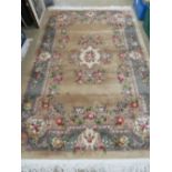 A Chinese woollen rug, gold ground with green floral decoration,