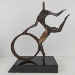 A bronze abstract sculpture of a gymnast with hoop, raised over black lacquered base,