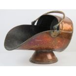 A copper coal scuttle having hinged handle over, raised over single foot, approx 45cm in length,